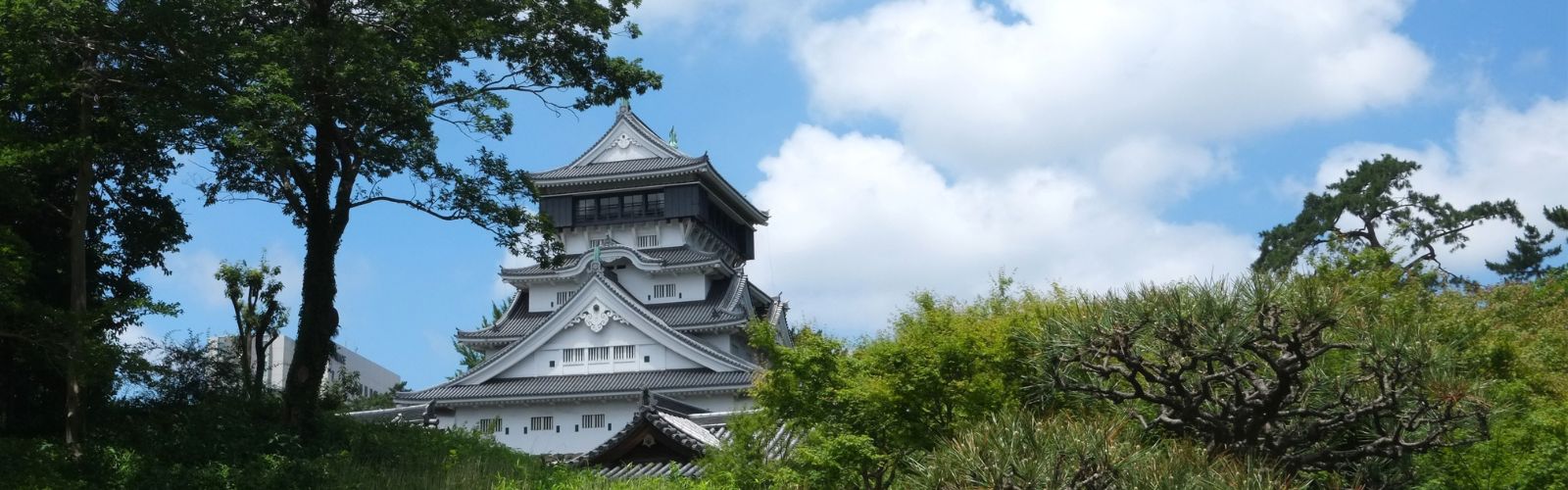 Green landscape with grass and trees, with tiered Japanese temple in the background